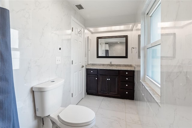 bathroom with marble finish floor, tile walls, visible vents, toilet, and vanity