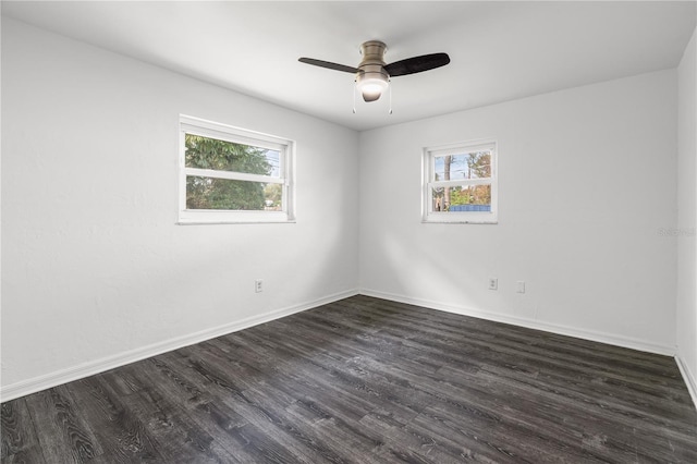 empty room with dark wood-style flooring, a ceiling fan, and baseboards