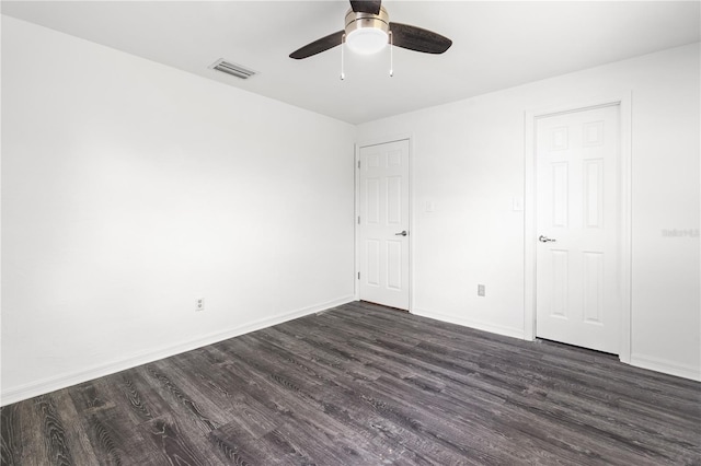 empty room featuring dark wood-type flooring, visible vents, baseboards, and a ceiling fan