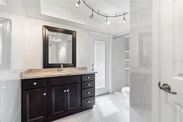 bathroom featuring toilet, marble finish floor, a marble finish shower, and vanity