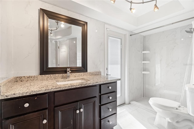 bathroom featuring toilet, marble finish floor, a marble finish shower, and vanity