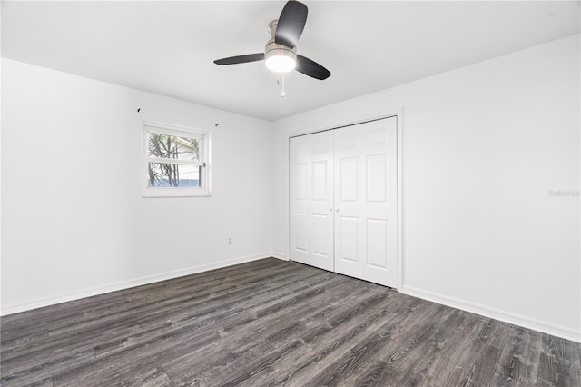 unfurnished bedroom with a ceiling fan, a closet, baseboards, and dark wood-style flooring