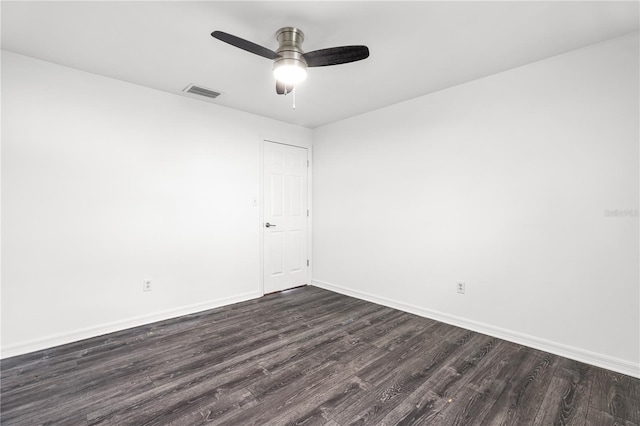 spare room with dark wood-style floors, visible vents, baseboards, and ceiling fan