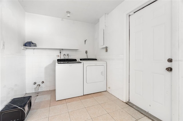 laundry area featuring light tile patterned floors, washing machine and dryer, laundry area, tile walls, and wainscoting