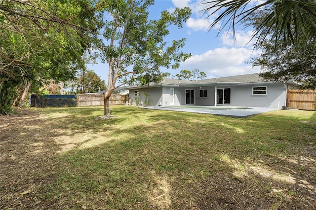 rear view of property featuring a yard, a fenced backyard, a patio, and stucco siding