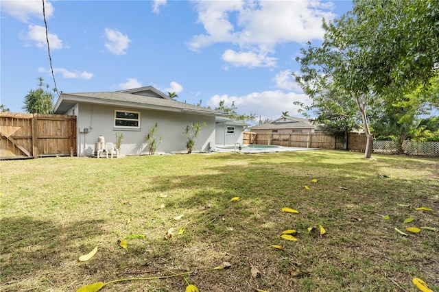 back of property featuring a lawn, a fenced backyard, a fenced in pool, and stucco siding