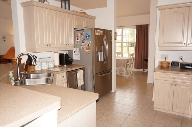 kitchen with appliances with stainless steel finishes, sink, light tile patterned floors, and light brown cabinetry