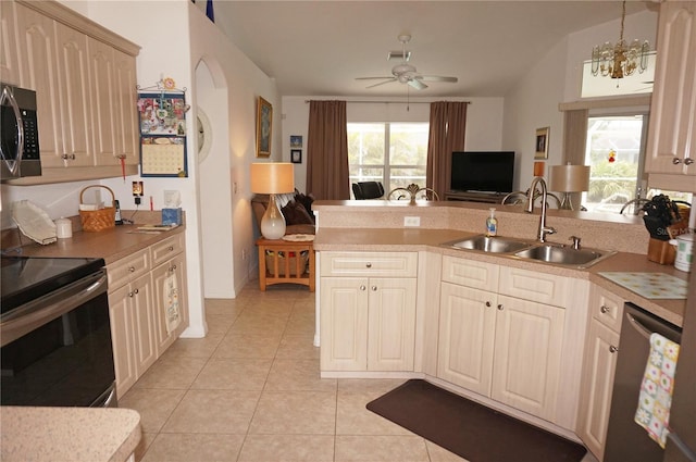 kitchen featuring sink, hanging light fixtures, stainless steel appliances, light tile patterned flooring, and ceiling fan with notable chandelier