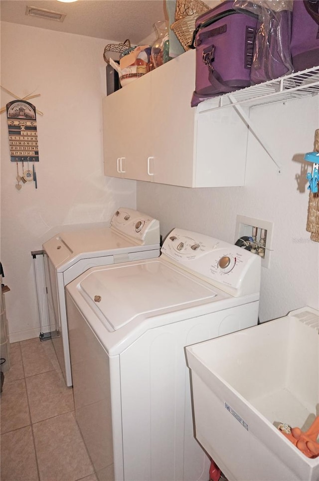 clothes washing area featuring cabinets, sink, washer and dryer, and light tile patterned floors