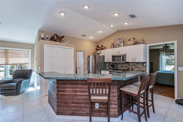 kitchen featuring lofted ceiling, a breakfast bar, stainless steel appliances, a healthy amount of sunlight, and white cabinets