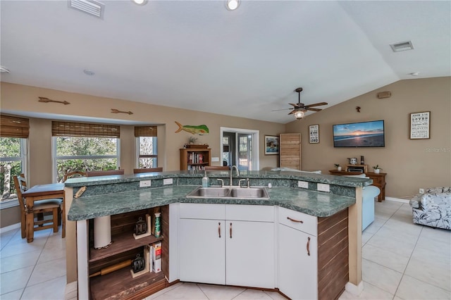 kitchen with vaulted ceiling, white cabinetry, sink, a kitchen island with sink, and light tile patterned floors