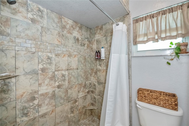 bathroom featuring a shower with curtain, toilet, and a textured ceiling