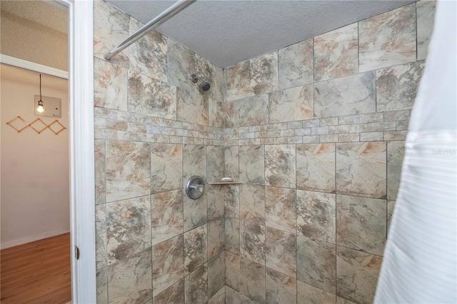 room details with hardwood / wood-style floors, curtained shower, and a textured ceiling