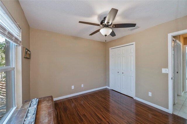 unfurnished bedroom with ceiling fan, dark hardwood / wood-style flooring, and a closet