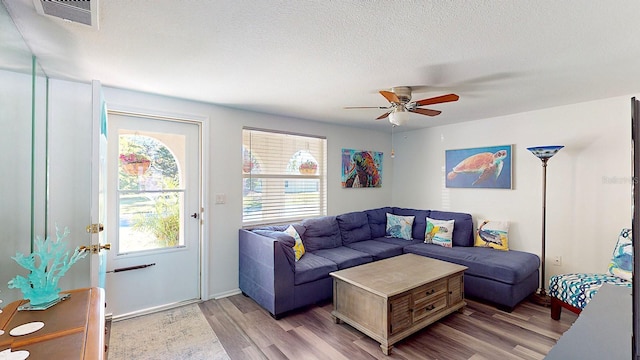 living room with a textured ceiling, ceiling fan, and light hardwood / wood-style flooring