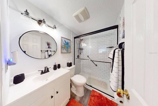 bathroom with hardwood / wood-style flooring, vanity, a textured ceiling, toilet, and walk in shower