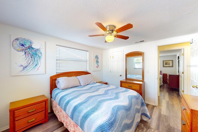 bedroom with ceiling fan, wood-type flooring, a closet, and a textured ceiling