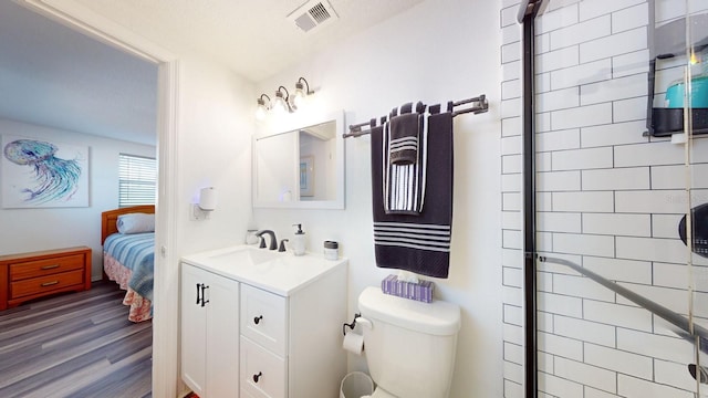 bathroom featuring vanity, wood-type flooring, a shower with shower door, and toilet