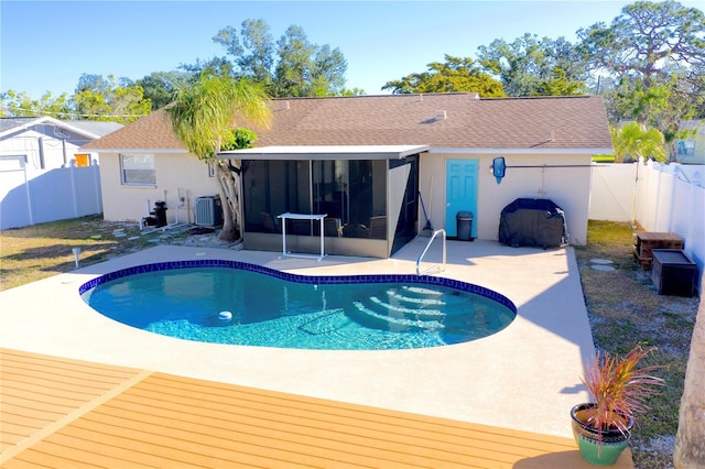 view of swimming pool with cooling unit, a patio area, and a sunroom