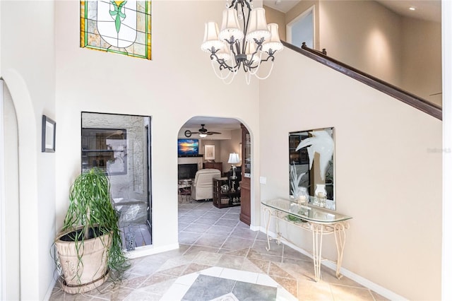 foyer entrance featuring ceiling fan with notable chandelier and a high ceiling