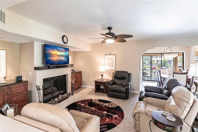 tiled living room with ceiling fan and a brick fireplace