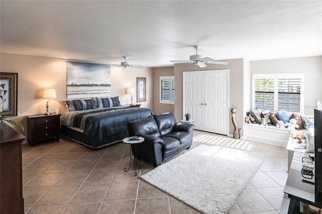 tiled bedroom with ceiling fan and a textured ceiling