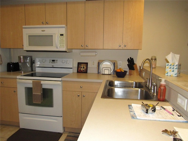 kitchen with white appliances, light brown cabinetry, and sink