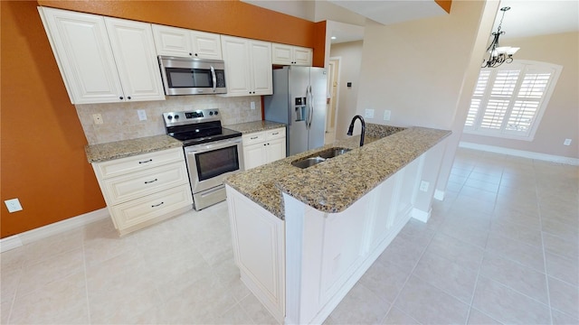 kitchen with sink, white cabinetry, stainless steel appliances, decorative backsplash, and decorative light fixtures