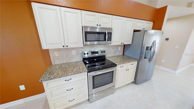 kitchen featuring tasteful backsplash, stainless steel appliances, light stone counters, and white cabinets