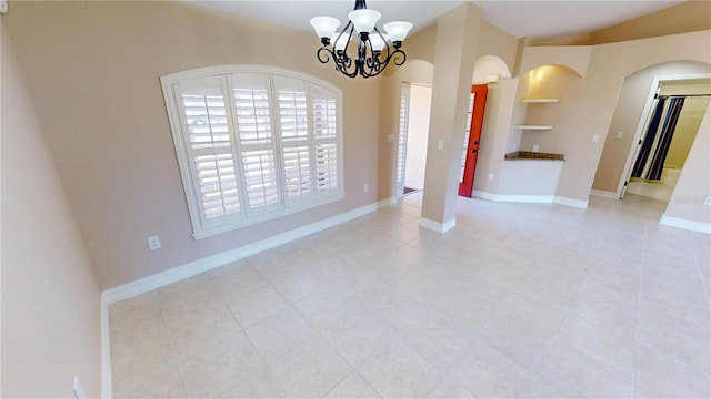 empty room with a notable chandelier, vaulted ceiling, and built in features