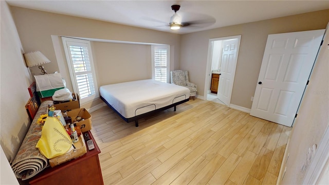 bedroom with multiple windows, connected bathroom, ceiling fan, and light wood-type flooring