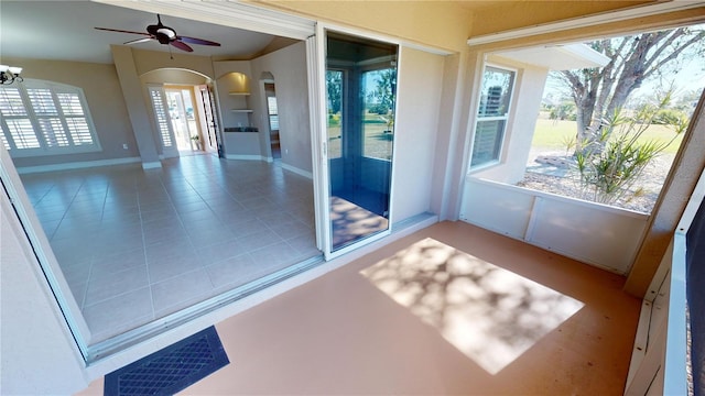 unfurnished sunroom with ceiling fan with notable chandelier and a wealth of natural light