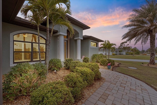 patio terrace at dusk featuring a lawn