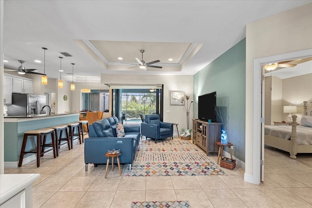 living room with a raised ceiling, ceiling fan, and light tile patterned flooring