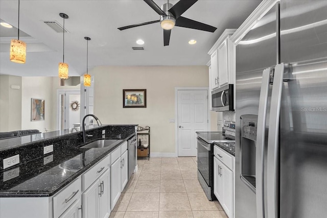 kitchen with appliances with stainless steel finishes, decorative light fixtures, white cabinetry, sink, and dark stone countertops