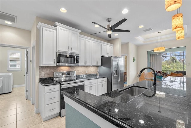 kitchen with stainless steel appliances, white cabinetry, hanging light fixtures, and a tray ceiling