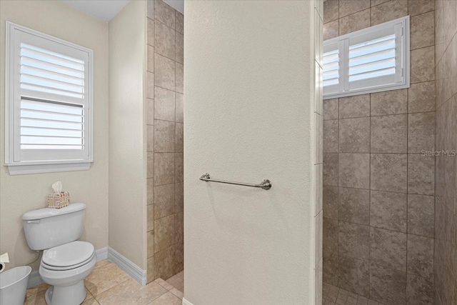 bathroom featuring tiled shower, tile patterned floors, and toilet