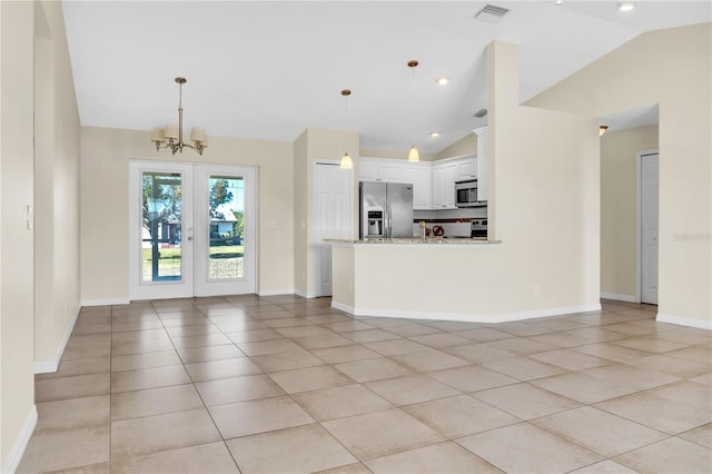 unfurnished living room featuring light tile patterned floors, a notable chandelier, vaulted ceiling, and french doors