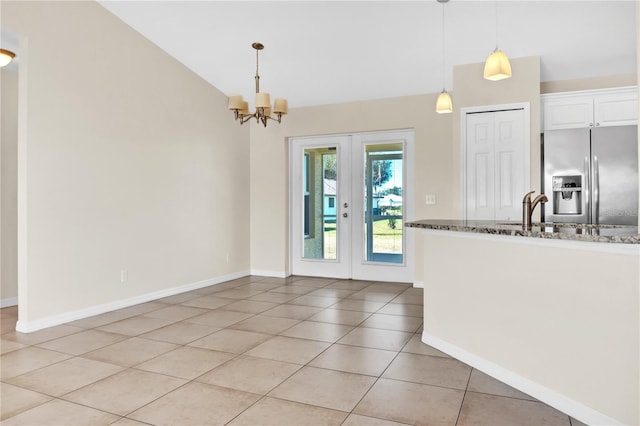 kitchen featuring decorative light fixtures, stainless steel fridge with ice dispenser, light tile patterned floors, dark stone counters, and white cabinets