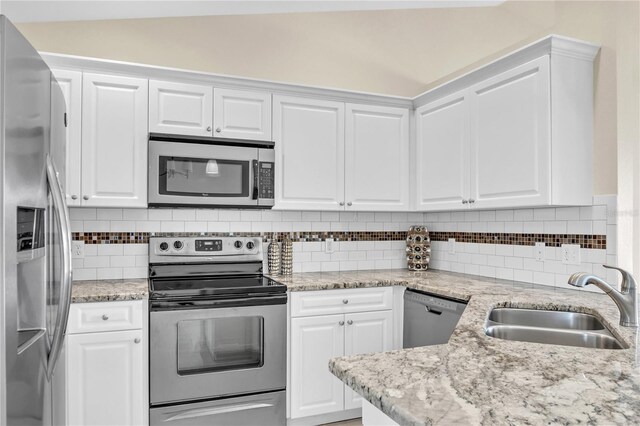 kitchen with appliances with stainless steel finishes, sink, white cabinets, and decorative backsplash