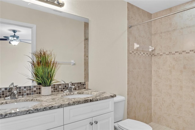 bathroom with a tile shower, tasteful backsplash, vanity, ceiling fan, and toilet