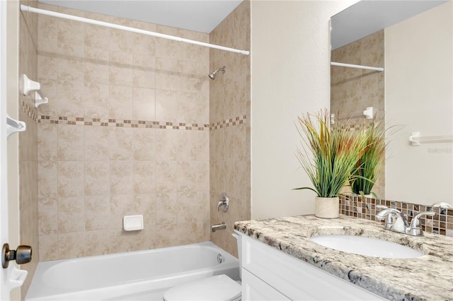 full bathroom featuring tiled shower / bath, vanity, and toilet