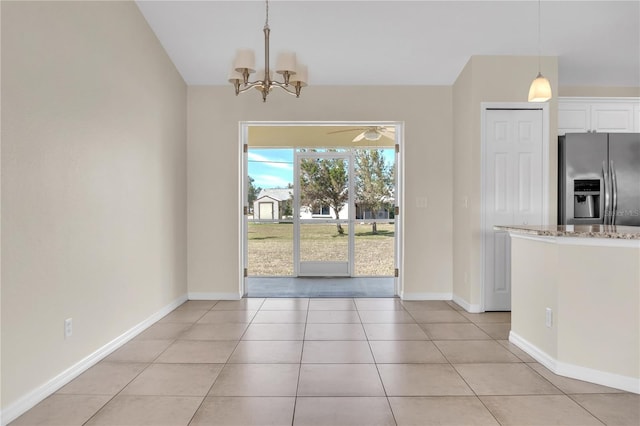 unfurnished dining area with light tile patterned floors and ceiling fan with notable chandelier