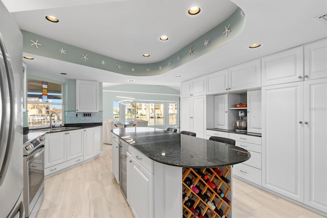 kitchen featuring a kitchen island, sink, white cabinets, and appliances with stainless steel finishes