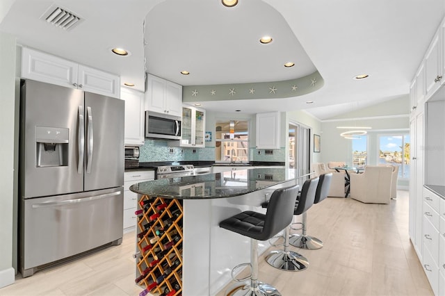 kitchen with sink, dark stone countertops, stainless steel appliances, white cabinets, and decorative backsplash