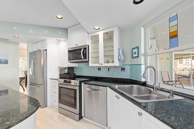 kitchen with tasteful backsplash, sink, white cabinets, dark stone counters, and stainless steel appliances