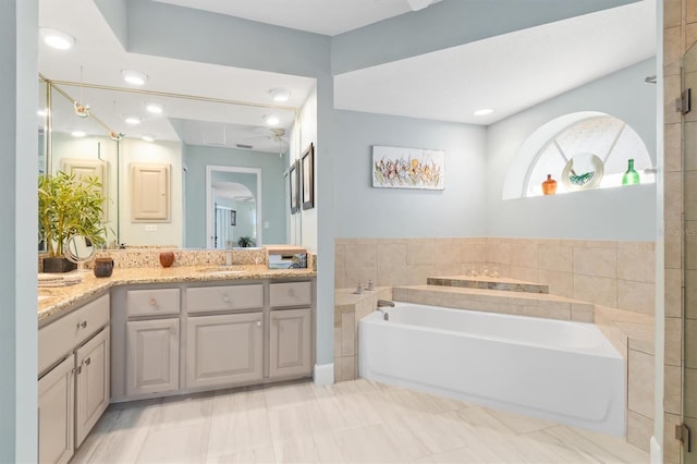 bathroom with a washtub, vanity, and tile patterned floors