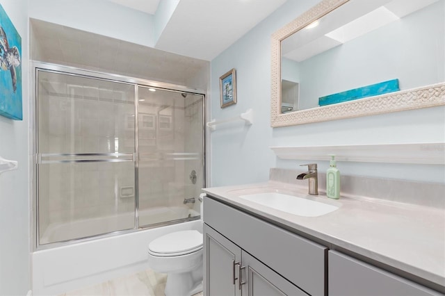 full bathroom featuring vanity, combined bath / shower with glass door, and toilet