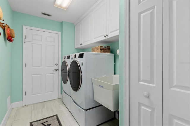 washroom with sink, washer and clothes dryer, and cabinets