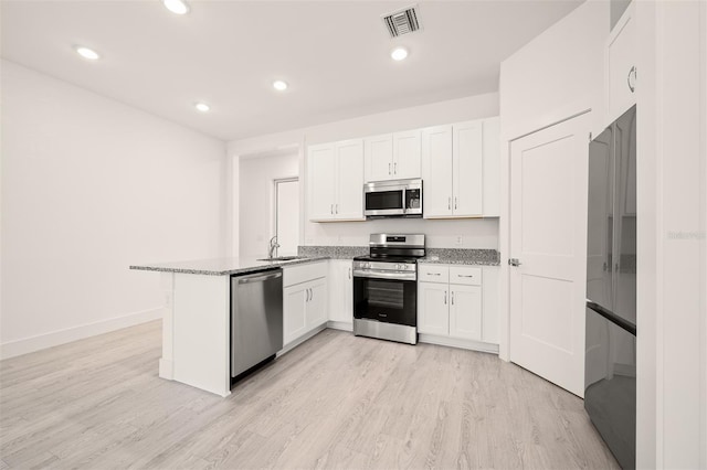 kitchen featuring stainless steel appliances, light hardwood / wood-style floors, light stone countertops, white cabinets, and kitchen peninsula